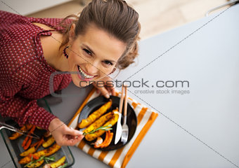 Portrait of happy young housewife serving baked pumpkin