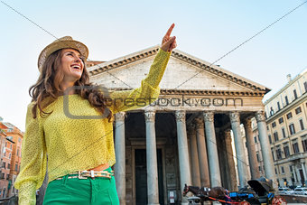 Portrait of happy young woman pointing in front of pantheon in r