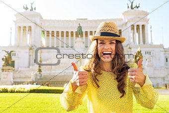 Portrait of smiling young woman showing thumbs up while standing