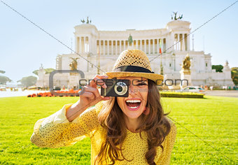 Smiling young woman taking photo on piazza venezia in rome, ital