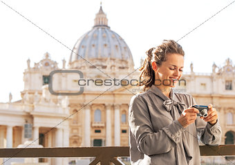Happy young woman checking photos in camera in front of basilica