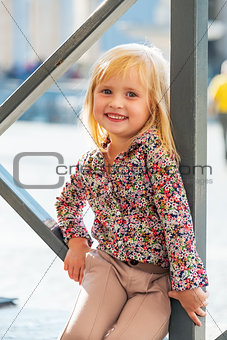 Portrait of happy baby girl sitting on street