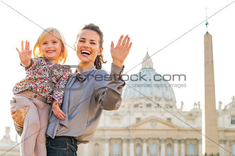 Portrait of happy mother and baby girl waving in front of basili