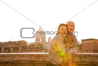 Portrait of smiling mother and baby girl on street overlooking r