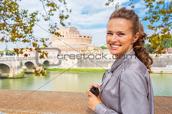 Happy young woman with photo camera standing on embankment near 