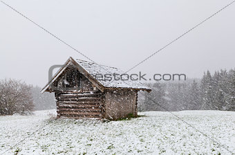 old wooden hut at snowstorm