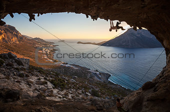 Male rock climber climbing along a roof in a cave
