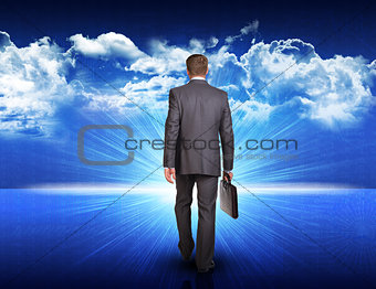 Businessman walking against blue landscape with rising sun