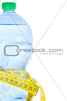 half plastic bottle with water, drops and measuring tape, concept of fitness and diet