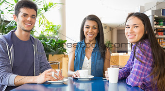 Young students smiling at camera in cafe