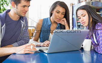 Young students doing assignment on laptop together