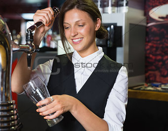 Happy barmaid pulling a pint of beer