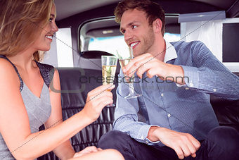 Happy couple drinking champagne in limousine