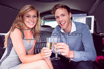Happy couple drinking champagne in limousine