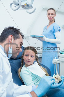 Male dentist teaching girl how to brush teeth