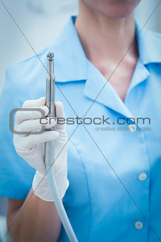 Mid section of dentist holding dental drill