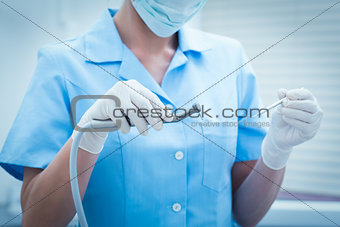 Mid section of dentist holding dental tools