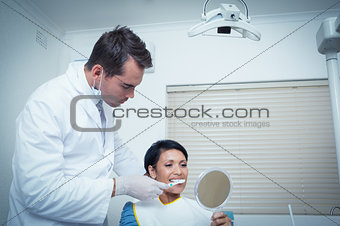 Male dentist brushing womans teeth