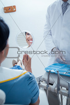 Smiling young woman looking at mirror