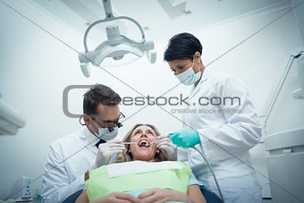 Dentist with assistant examining womans teeth