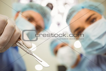 Young surgeons looking down at camera holding scalpel