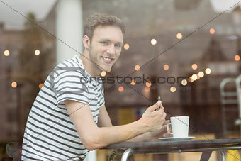 Smiling student sitting with a hot drink
