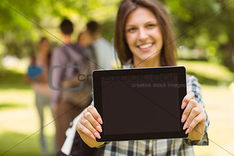 Smiling student with a shoulder bag and showing screen at tablet pc