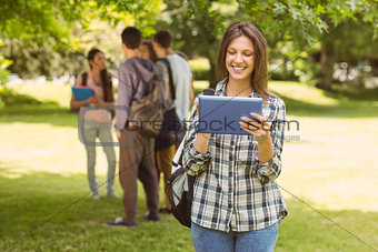 Smiling student with a shoulder bag and using tablet computer