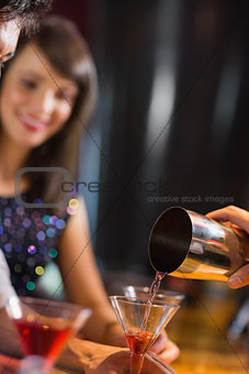 Bartender pouring cocktail for customers