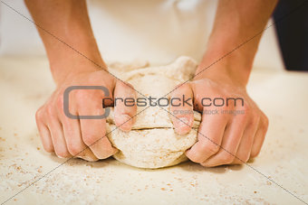 Baker kneading dough at a counter