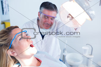 Dentist examining a patients teeth in chair under bright light