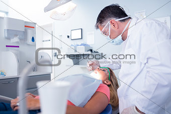 Dentist in surgical mask examining a patients teeth