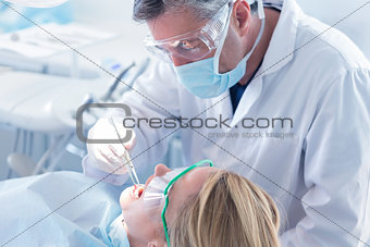 Dentist examining a patients teeth with surgical mask and gloves