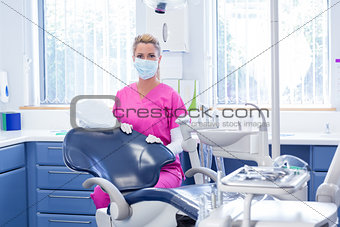 Dentist in mask looking at camera beside chair