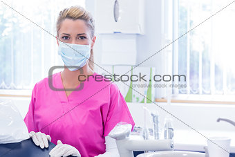 Portrait of a dentist in mask looking at camera beside chair