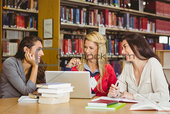 Smiling mature student with classmates using laptop