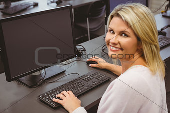 Mature student in computer room smiling at camera