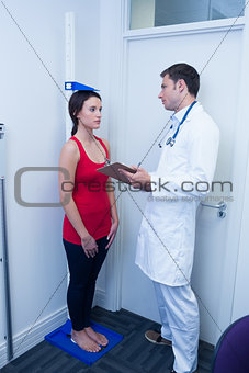 Confident doctor measuring patients height