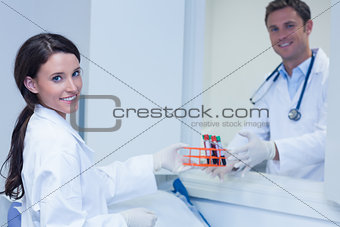 Smiling biologists with blood sample looking at camera
