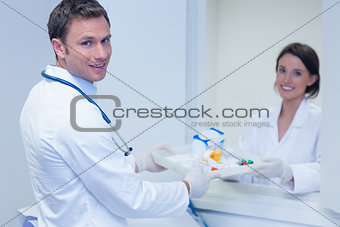 Doctor giving tray with blood sample to his colleague