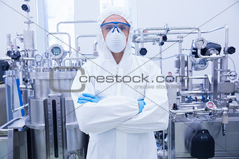 Scientist in protective suit standing with arms crossed
