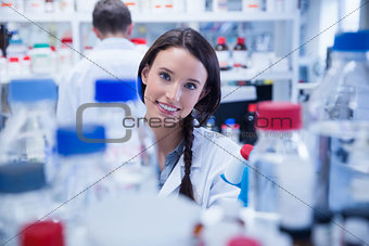 Portrait of a smiling chemist holding a bottle of chemicals