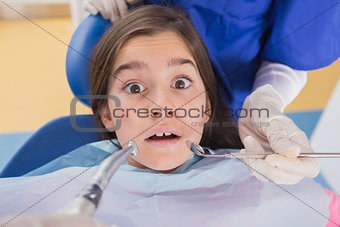 Dentist and his dental assistant examining a terrified young patient