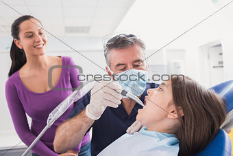 Pediatric dentist examining young patient with a suction tube