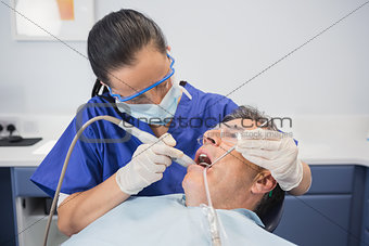 Dentist examining a patient with suction hose