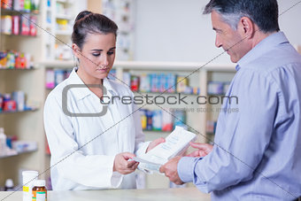 Customer handing a prescription to a trainee