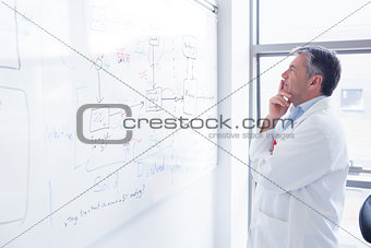 Focused scientist looking equation on whiteboard
