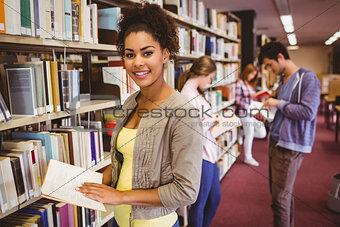 Happy student taking book from shelf