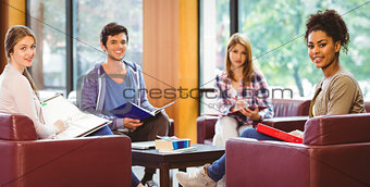 Students sitting on couch revising and smiling at camera