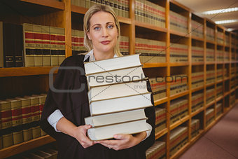 Lawyer holding heavy pile of books standing